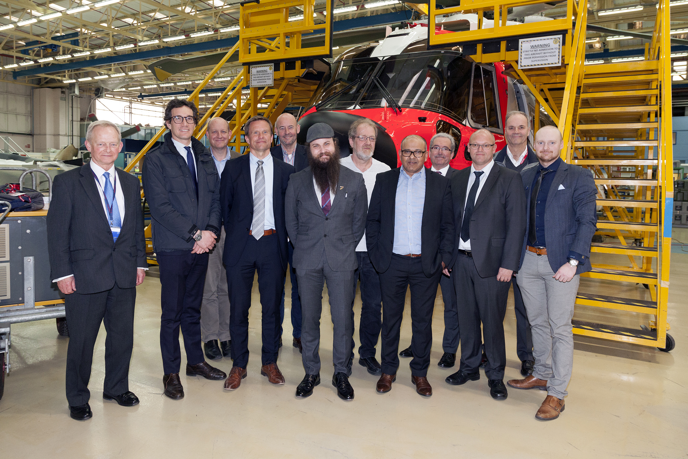 Syv representanter fra Helikopterutvalget besøkte Leonardo Helicopters fabrikk i Yeovil forrige uke. Fra utvalget deltok Kjetil Larsen (4 fra venstre), Erik Hamremoen (5 fv), Henrik Fjeldsbø (6 fv), Frode Nirisen (7 fv), Mohammad Afzal (8 fv), Atle Espen Helgesen (10 fv) og Tom Stian Beitland (12 fv). De andre personene på bildet er representanter fra Leonardo. I bakgrunnen ses en norsk Aw101.